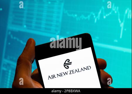 In this photo illustration, the New Zealand's flag carrier airline Air New Zealand logo is seen displayed on a smartphone with an economic stock exchange index graph in the background. Stock Photo