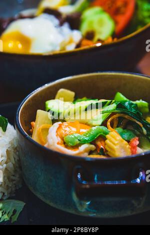 Thai green seafood curry dish with white rice and fresh salad and Bibimbap traditional Korean dish of mixed rice with meat, egg and vegetables. Stock Photo