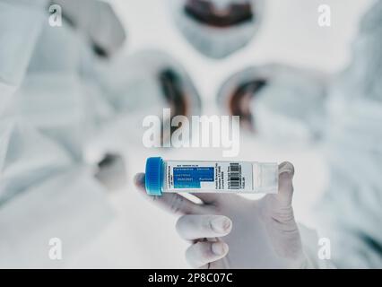 Healthcare scientists holding a vaccine, test tube and medical treatment while doing covid research in a laboratory. Group of science technicians Stock Photo