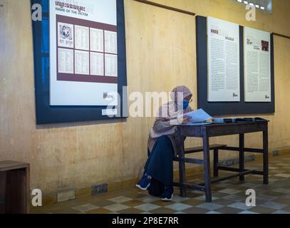 A Cambodian muslim woman reads testimonies in a former classroom in the ...