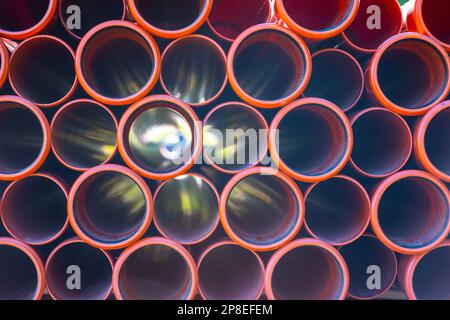 Large pile of orange plastic PVC pipes Stock Photo