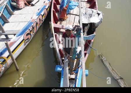fisherman on a traditional wooden boat ready to set sail to catch fish on a sunny day Stock Photo