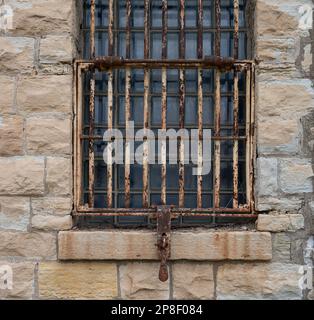 A close-up image of a small window with rusty metal bars across the opening Stock Photo