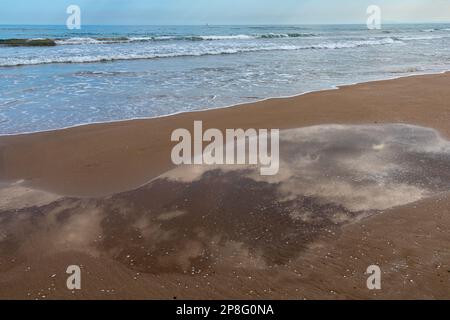 Mar y charco de agua en la playa con el reflejo de las nubes Stock Photo