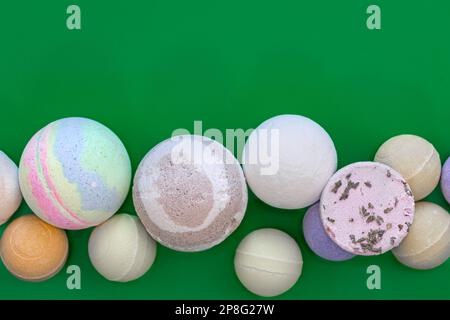 Multicolored bath bombs on a green background, top view. Stock Photo