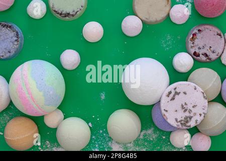 Multicolored bath bombs on a green background, top view. Stock Photo