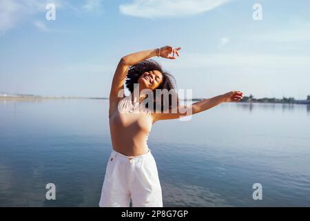 Close up portrait of happy african american female teenage smiling sweetly at the camera. Mixed race black girl with afro curls hairstyle. Laughing te Stock Photo