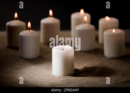 candles with burning flame, in the sand Stock Photo