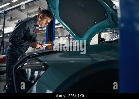 Auto mechanic in overalls near wheel of car Stock Photo - Alamy