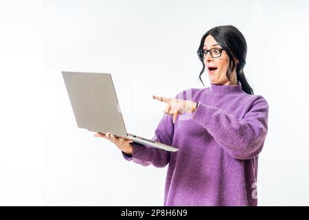 A surprised young Caucasian female holding and pointing at a laptop isolated on a white background. Stock Photo