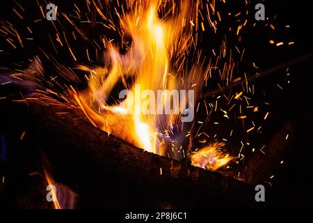 Sparks fly from a burning wood fire Stock Photo