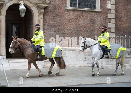 City of London mounted police officers ride horses through Bow Churchyard in front of St Mary-le-Bow Church. London, England, UK Stock Photo