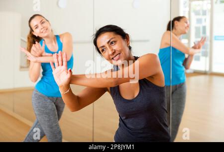 Cheerful hispanic woman practicing vigorous dance in group class Stock Photo