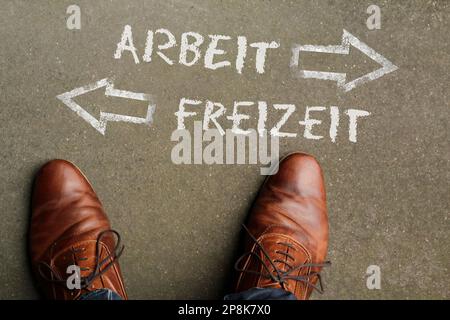 Work Life Balance: The words Arbeit and Freizeit (German for work and spare time) written on the floor with arrows pointing in opposite directions Stock Photo