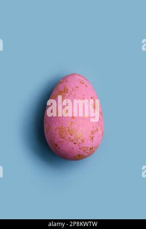 Easter greeting card featuring a minimalist decorated pink Easter egg on a pastel blue background. Perfect for web banners, greeting cards, social med Stock Photo