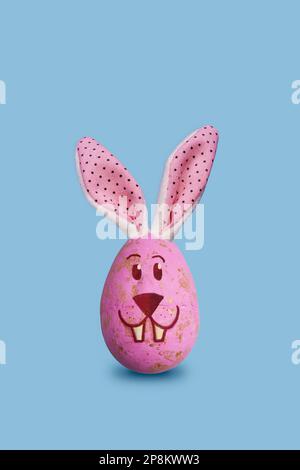 Easter bunny egg decoration with bunny ears and bunny face on pastel blue background. Perfect for Easter greeting cards, social media posts, and web b Stock Photo