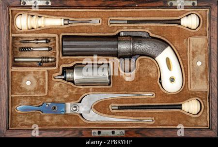 Cased ancient six barreled revolving percussion pistol also called 'Pepperbox' from 19th century, top view closeup firearm with accessories Stock Photo