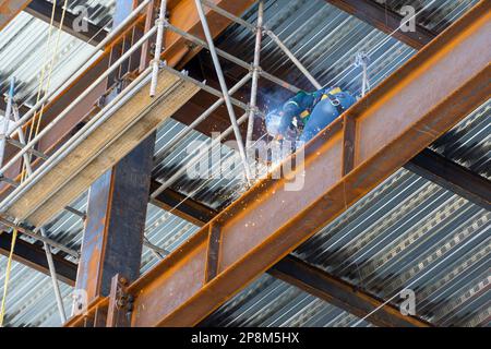 A construction worker using an angle grinder on a scaffold Stock Photo