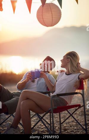 couple laughing at sunset, looking each other, toasting, enjoying Stock Photo