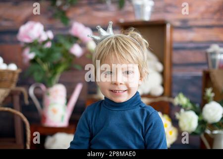 Beautiful toddler blond boy, wearing little crown, pretending to be prince, child playing imaginary games Stock Photo