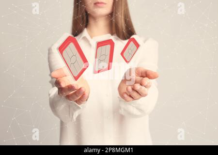 Woman demonstrating SIM cards of different sizes on light background, closeup Stock Photo