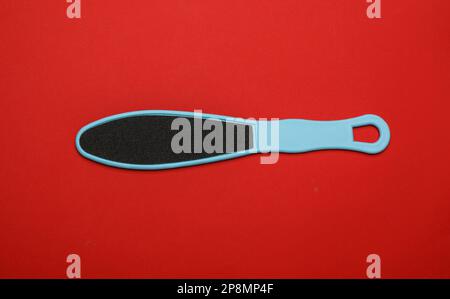 Light blue foot file on red background, top view. Pedicure tool Stock Photo
