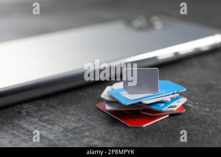 SIM cards and mobile phone on grey table, closeup Stock Photo
