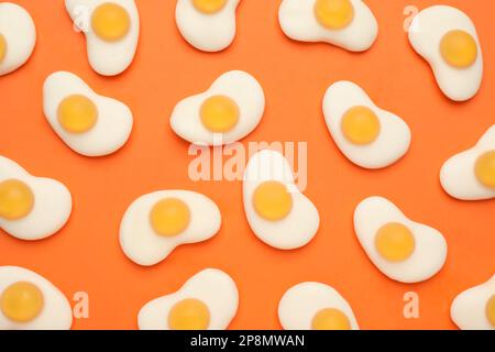 Delicious gummy fried egg candies on orange background, flat lay Stock Photo