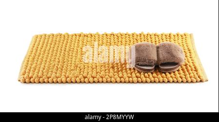 New yellow bath mat with fluffy slippers isolated on white Stock Photo