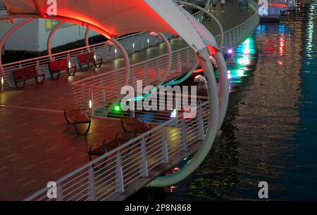 People enjoying time walking on pedestrian riverwalk trail alongside river water in downtown district of Tampa city in Florida, USA. Recreational area Stock Photo