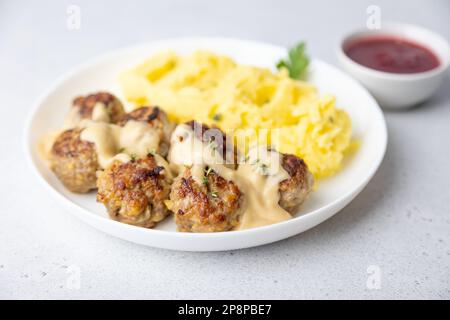 Swedish noisettes (fricandel) with mashed potatoes, Brune Sos creamy sauce and lingonberry (cranberry) sauce. Traditional meatballs with garnish. Sele Stock Photo