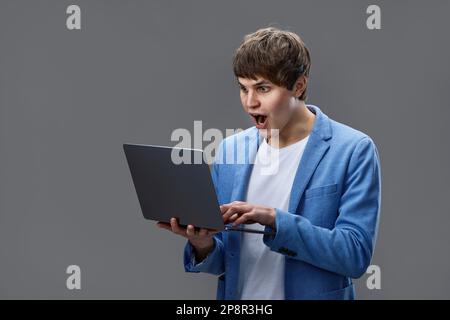 caucasian young man using laptop isolated on gray background Stock Photo