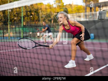 Young woman in skirt playing tennis on court Stock Photo