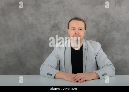 Sadly sitting at the table alone is a man in a gray suit Stock Photo