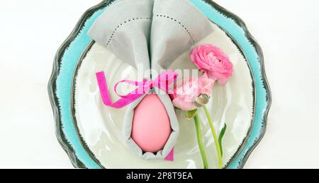 Easter table setting and decoration, Easter egg in a gray napkin on plates set, white background Stock Photo