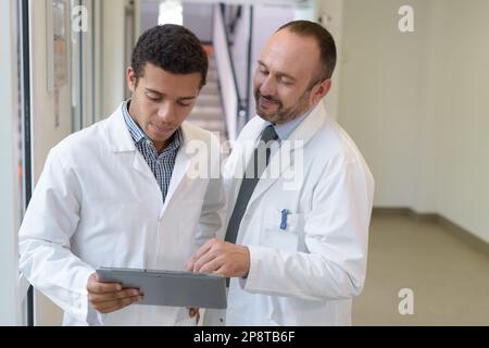 senior and junior doctors looking at tablet pc Stock Photo