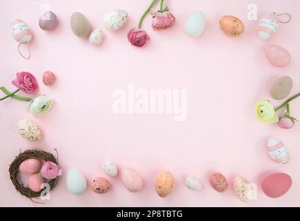 Happy Easter card template, flat lay. Pastel color Easter egg, Spring flowers and season decoration frame on pink background, top view, copy space. Stock Photo