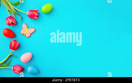 Happy Easter card template, flat lay. Easter egg, tulips and season decoration on bright blue background, top view, copy space. Stock Photo