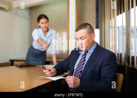 Shocked office employe reading papers with dissatisfied female manager Stock Photo