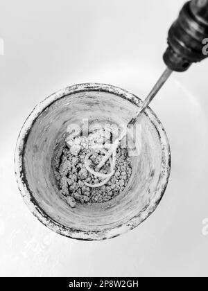 Mixer is placed inside an old plastic bucket. Process of manual mixing construction putty. Preparation for putty work. Close-up. Copy space. Selective Stock Photo