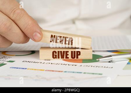 Business concept. On the table are business charts and diagrams in the hands of a wooden block with the inscription - Never Give Up Stock Photo