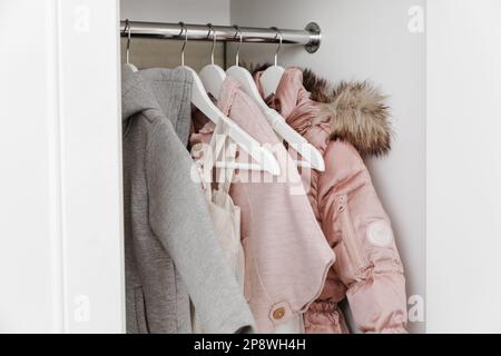 Hangers with stylish clothes for a girl in the white closet. Stock Photo