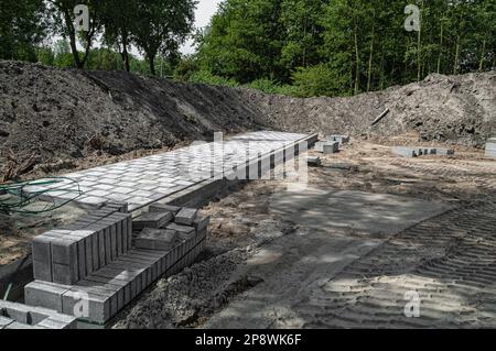 open building site surrounded by sand mountains where a sidewalk will be constructed Stock Photo