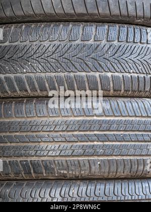 Used car tires stacked in piles.Worn out rubber tires. Stock Photo