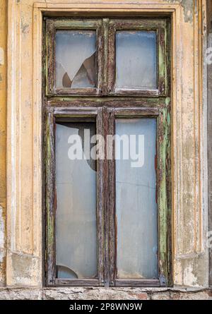 Detail with a broken wooden frame window . Worn out building in the center of Bucharest, Romania. Stock Photo