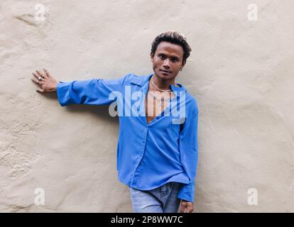 Young handsome guy leaning against a wall and looking at camera Stock Photo
