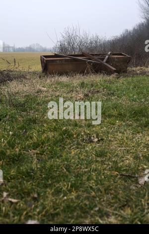 Rusty  steamroller lying next to a cultivated field on a misty day in winter Stock Photo