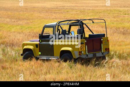 BLAKENEY, NORFOLK, ENGLAND -  JULY 13, 2022: Land Rover Defender parked in field of wheat Stock Photo