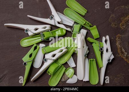 Broken cheap plastic clothes pegs on a piece of grey slate Stock Photo