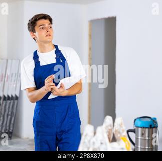 Young foreman making task list during works in building under construction Stock Photo